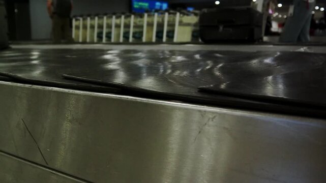 Close-up of suitcases moving on a baggage claim conveyor belt inside Tbilisi airport terminal.