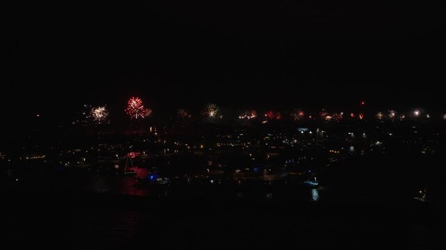 Fireworks over the Dutch town of Urk in the Netherlands, with the traditional red emergency flares from the fishing vessels being lid.