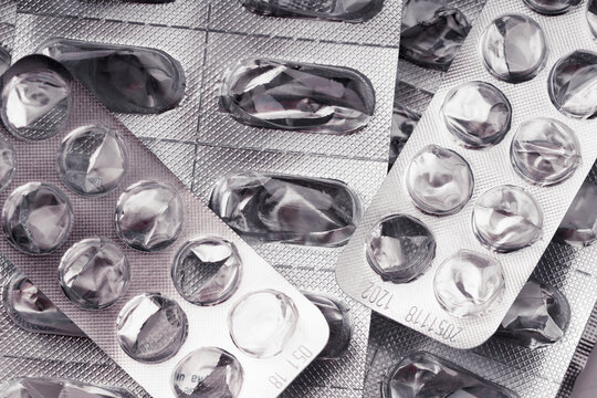 Pile of empty blister packs of pills close up. Concept of medical waste management, environmental pollution by plastic pharmaceutical packaging, expensive healthcare cost and end of treatment. Macro.