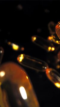 Glowing amber softgels floating in darkness, luxury supplement Filmed on a high-speed camera at 1000 fps.
