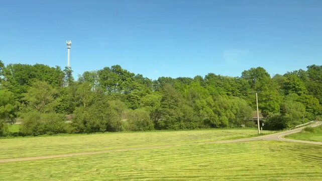 Train traveling over elevated concrete railway bridge in green countryside with trees and clear blue sky  video footage. Transportation infrastructure. 