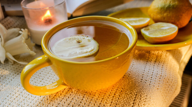 Cozy scene with hot lemon tea, lit candle, and an open book for relaxation