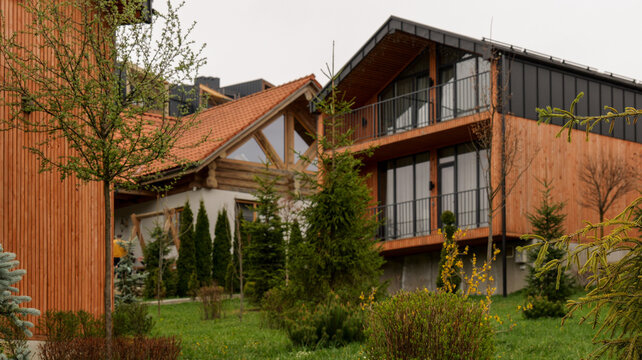 Modern wooden eco-lodge with balconies surrounded by lush green trees and manicured lawns