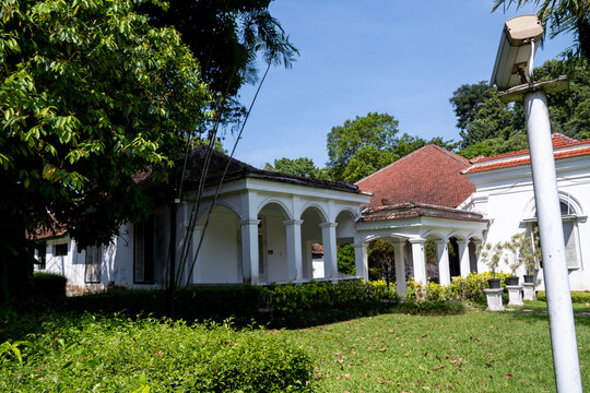 The historic Melchior Building, built in 1884, stands within Bogor Botanical Gardens surrounded by lush tropical greenery.	