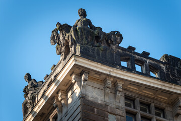 Historic building corner with rooftop statues under blue sky © Mirko