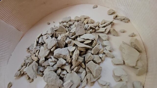 High-quality close-up shot of raw bentonite clay rocks, traditional skincare mineral powder, organic earth material used in spa and beauty treatments, top view, natural texture.