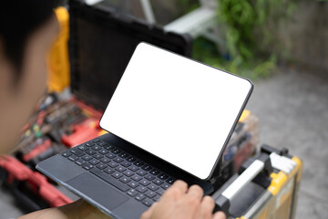 A technician in a safety vest holds a tablet with blank white screen mockup outdoors, ideal for field service, maintenance, and technology app concepts. © Stella 16