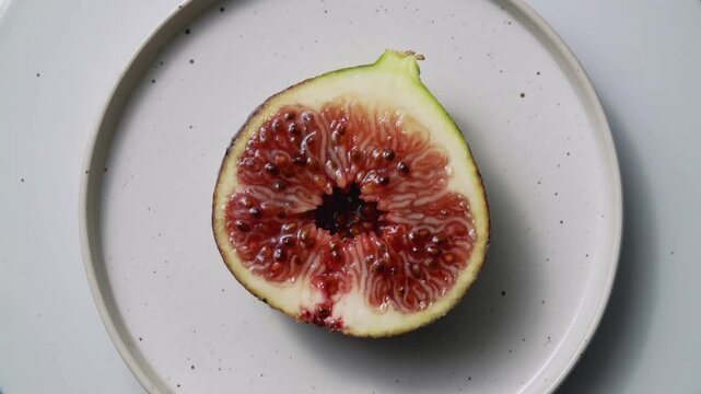 Fresh halved fig on a ceramic plate top view