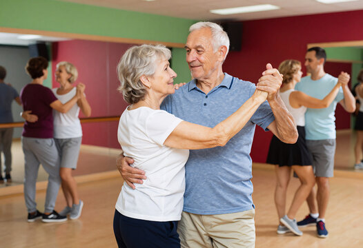 Senior couple dancing salsa in colorful class for adults
