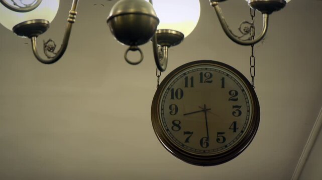 Vintage Railway Clock Hanging Near Antique Bronze Chandelier Lamp in Warm Room - 4K