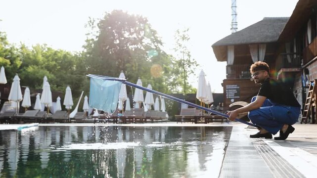 Maintaining a swimming pool with a skimmer net, removing debris from the clear water in an outdoor resort setting