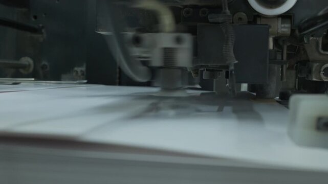 Industrial vacuum suction cups lifting and separating paper sheets on automatic feeder mechanism in printing house. Extreme close up shot