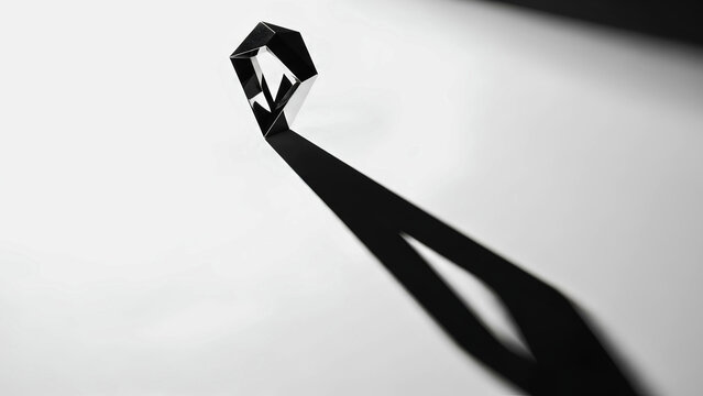 A shadow of a polygon object creates an abstract, geometric pattern on a white surface