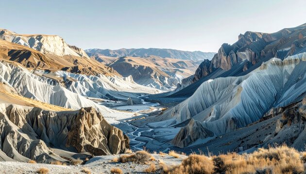 Sunlit badlands canyon with stratified hills and a winding riverbed