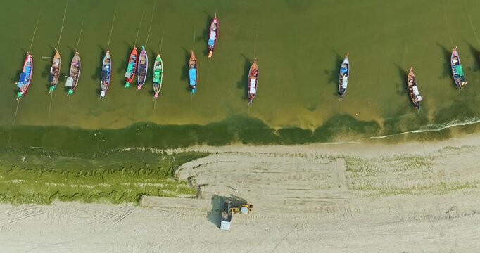 Aerial top down view of green algae spreading across the sandy shoreline of Patong Beach, Phuket. with a tractor actively cleaning the coast. The environmental maintenance, coastal ecosystem changes