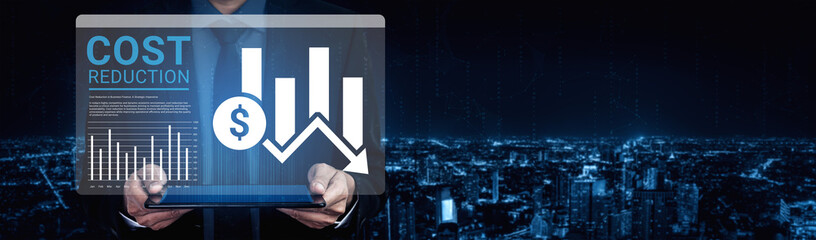 A businessman stands against a stunning nighttime cityscape, holding a tablet displaying graphs and data focused on cost reduction and financial performance analysis. Ledger © InfiniteFlow