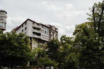 Fototapeta premium Apartment buildings rise above green trees under cloudy sky in Belgrade Serbia. Concept of urban living, residential estate and peaceful city lifestyle