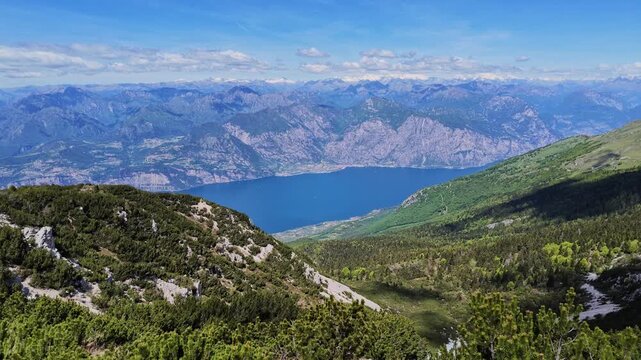 Panoramic high altitude view from Monte Baldo overlooking deep blue Lake Garda, Italian Alps mountain landscape, travel destination, scenic nature scenery