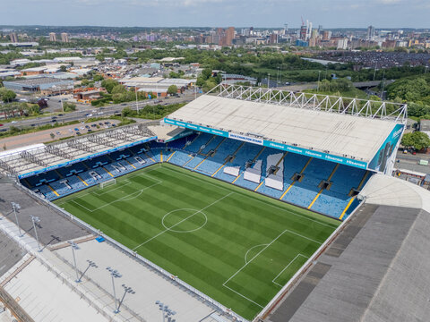Elland Road football stadium in Leeds, West Yorkshire, England, aerial view across the pitch and main stand towards Leeds city centre skyline, showing the famous Yorkshire football ground and urban la