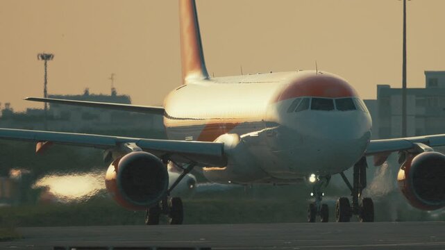 Airplane taxiing on the runway at sunset near the airport in the evening