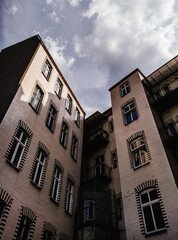 Low angle view of a vintage brick apartment building courtyard or tenemy house well under a dramatic cloudy sky © lukaszbrozek