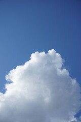 Obraz premium Cinematic beautiful fluffy white cumulus cloud in clear bright blue sky sunny day panorama background copy space vertical