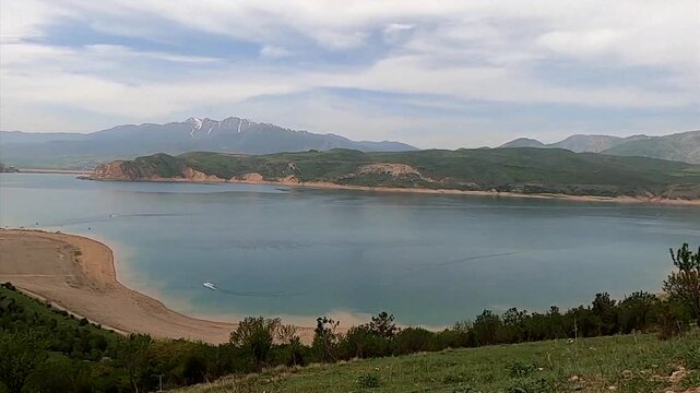 Scenic panning shot of Charvak reservoir with a speedboat in Uzbekistan