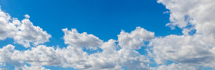 Obraz premium Bright blue sky with fluffy white cumulus clouds on sunny day, fresh summer atmospheric panoramic background