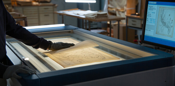 Archivist inspecting historical map on light table with archivist preservation research document antiquities scanning professional cartography restoration historical heritage digitization