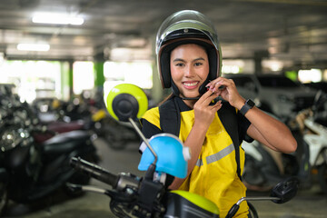 Smiling Female Delivery Courier Fastening Helmet in Parking Garage © Ranta Images
