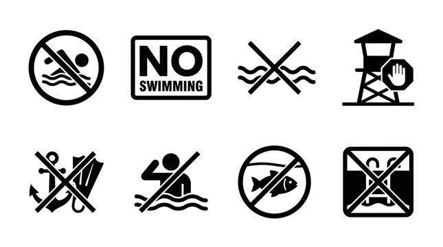 A set of black and white warning signs prohibit swimming and fishing in a restricted area near a lifeguard tower.