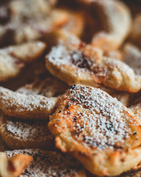 Close-up portrait of homemade traditional Polish faworki chrust pastry sprinkled with powdered sugar, delicious sweet crispy dessert culinary concept background