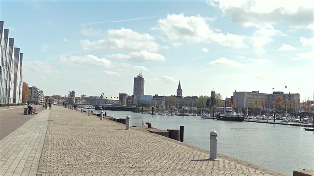 Dunkirk waterfront promenade with marina boats and city skyline in France