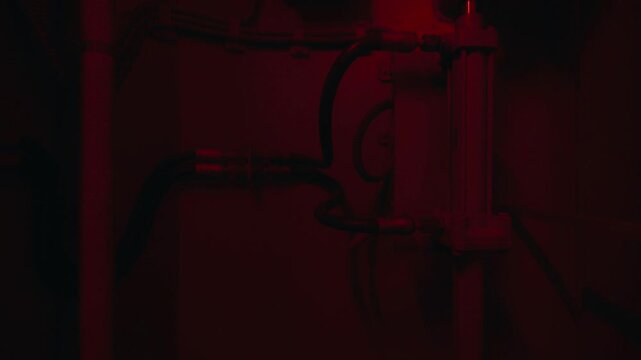 Mechanical components of an elevator moving up inside a dark shaft illuminated by a red light
