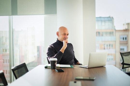 Mid-aged businessman sitting in a meeting room table and working on laptop