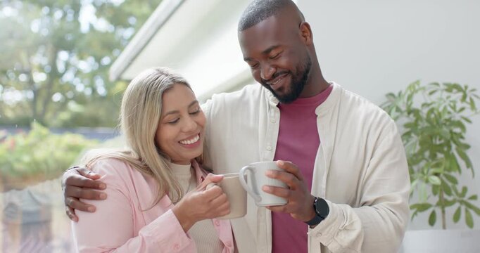 Diverse couple by glass door holding mugs, man draping arm, smiling glances drawing them closer