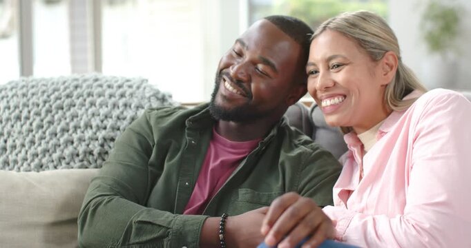 African American couple woman smiling at man, leading to laughing and leaning on sofa with bracelet