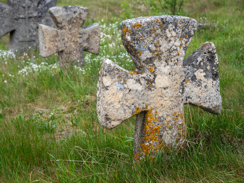 Close view of old weathered stone cross in grass near Pidkamin historic site