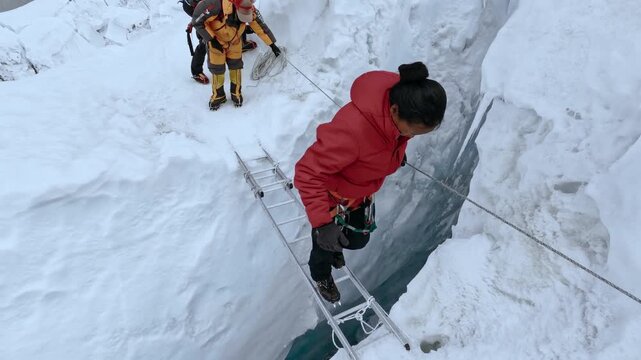 Group of climbers traversing a dangerous glacial crevasse using a ladder in the Himalayas