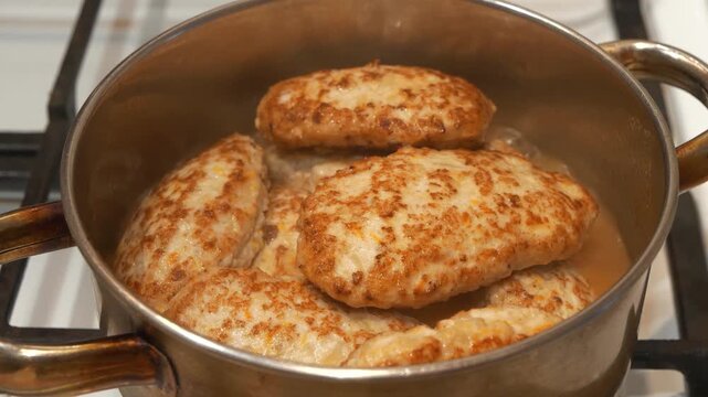 Cooking, stewing meat. Meat patties are cooked in metal cooking pot with boiling water, close-up shot. Meat cutlets are stewed in saucepan after being fried in frying pan
