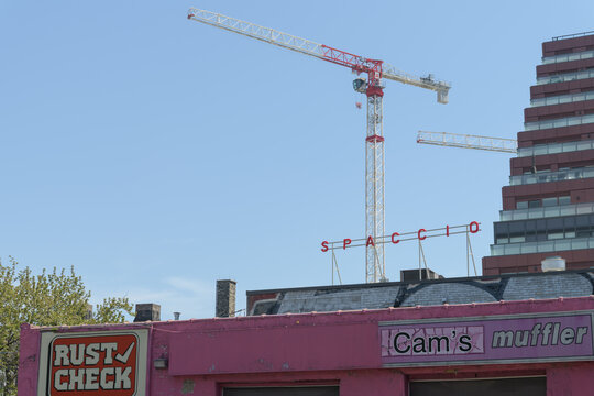 construction site cranes, rooftop sign of Spaccio, and facade branding of Thruway Muffler / Cam's Auto Service, 475 King St E, Toronto