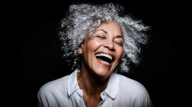 Close-up of a smiling stylish lady in a white blouse against a black studio background. Concept of sophisticated beauty and longevity.