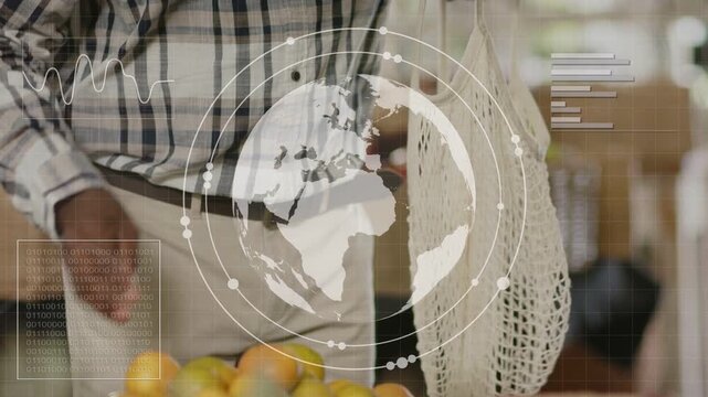 Senior man hovering over grocery starting globe and charts while picking oranges to fill mesh bag