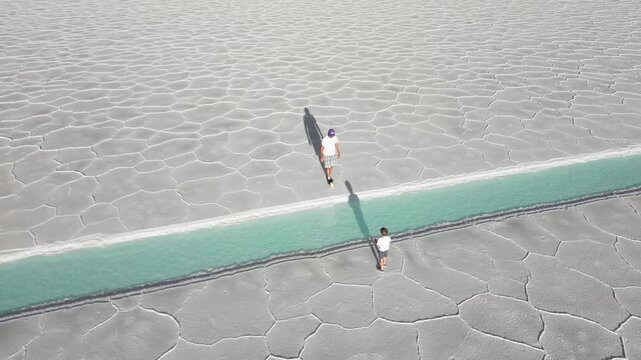 Father and boy playing soccer beside turquoise saltwater pools on the salt flats of Salinas Grandes, Jujuy, Argentina