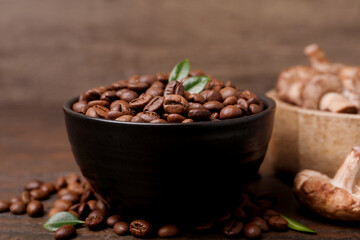 Fototapeta premium Coffee beans and mushrooms on wooden table, closeup