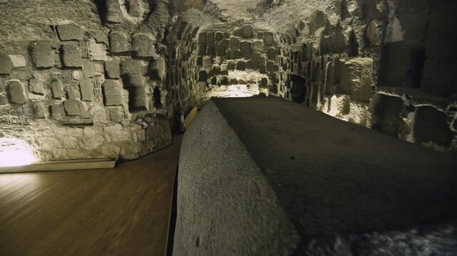 Mysterious subterranean gallery inside Serapeum of Saqqara, Egypt, rough limestone walls, carved arches and dramatic lighting leading to giant granite burial vessel.