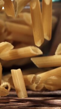 Penne pasta falling on a wooden table. Filmed on a high-speed camera at 1000 fps. High quality FullHD footage