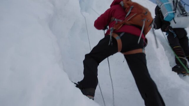 Two mountaineers with ropes and crampons ascending a snow covered mountain face in winter