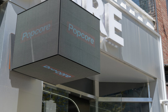 digital cube sign projecting from the facade of Popcore, a toy store, located at 342 Queen St W, Toronto