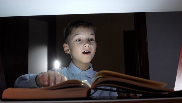 Young boy with wide eyes and an open mouth reacting in awe and surprise to an open storybook emitting a mysterious light, symbolizing imagination, education, and the magic of reading